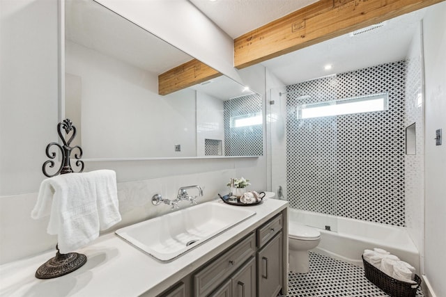 full bathroom with tiled shower / bath, vanity, beamed ceiling, and toilet