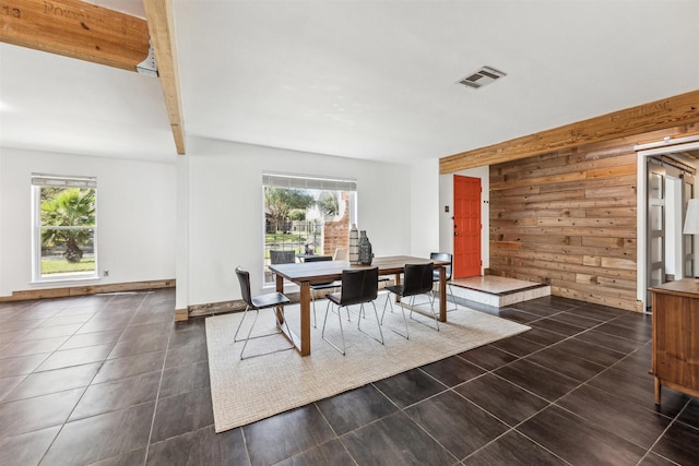 dining room featuring plenty of natural light, wood walls, and beam ceiling