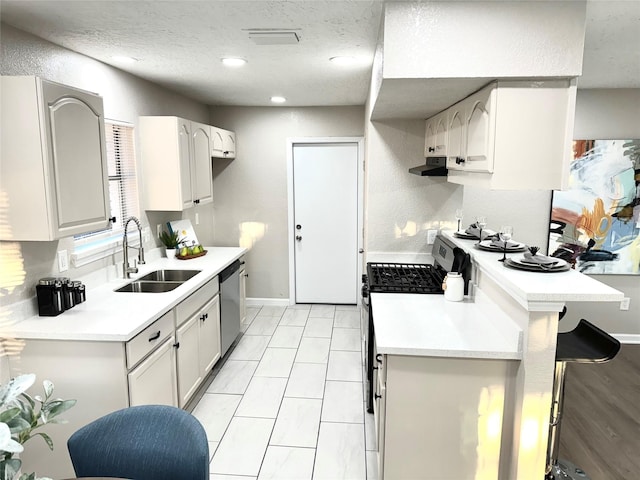 kitchen with stainless steel dishwasher, a breakfast bar, gas range, sink, and white cabinets