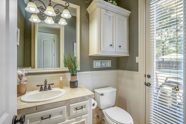 bathroom featuring vanity, an inviting chandelier, and toilet