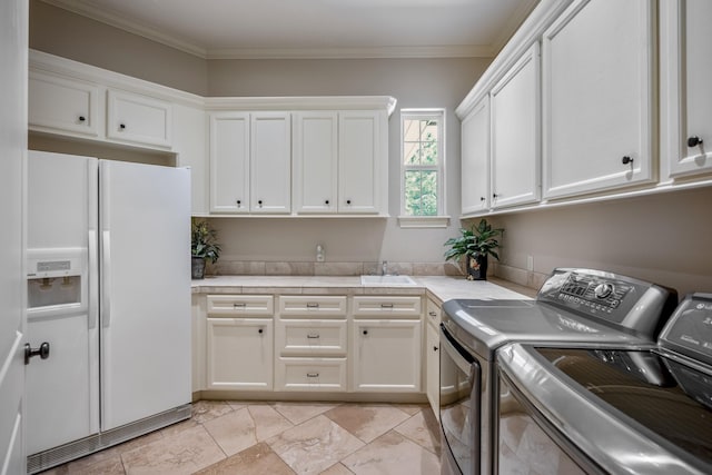 laundry area featuring cabinets, ornamental molding, separate washer and dryer, and sink