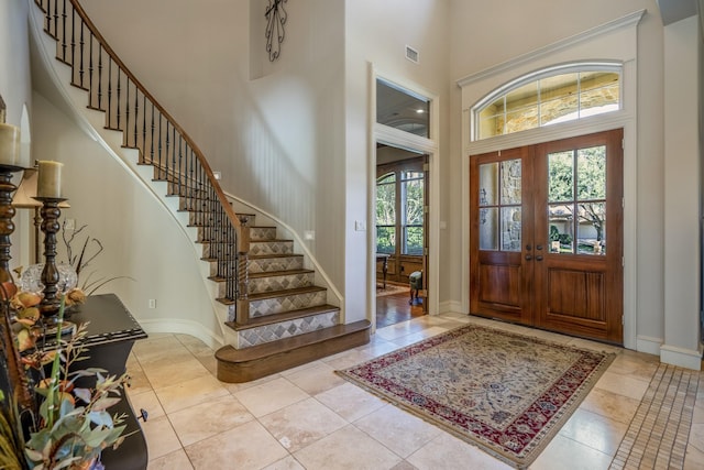 entryway featuring french doors, light tile patterned flooring, and a high ceiling