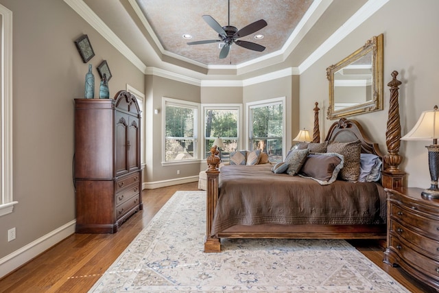 bedroom featuring crown molding, ceiling fan, a tray ceiling, and hardwood / wood-style flooring