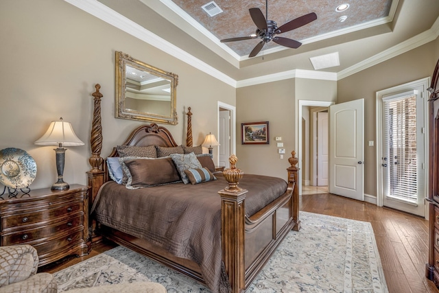 bedroom featuring crown molding, light wood-type flooring, ceiling fan, and a tray ceiling