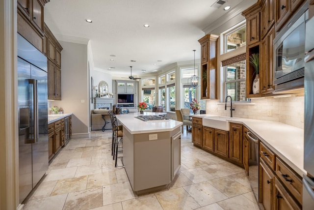 kitchen featuring sink, a breakfast bar area, a center island, built in appliances, and ceiling fan with notable chandelier