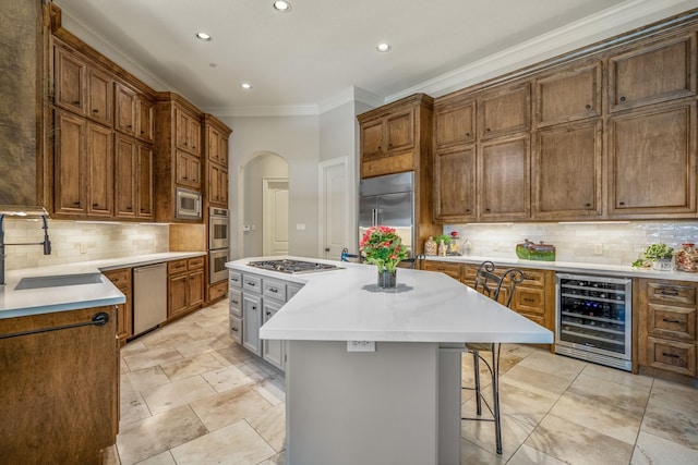 kitchen with wine cooler, sink, built in appliances, a kitchen island, and decorative backsplash