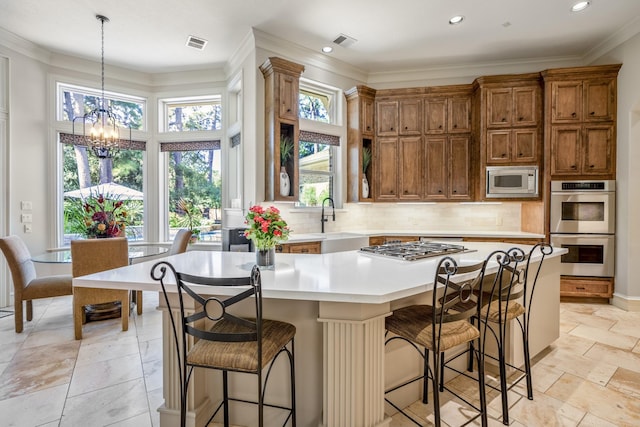 kitchen featuring a center island, a chandelier, appliances with stainless steel finishes, pendant lighting, and backsplash