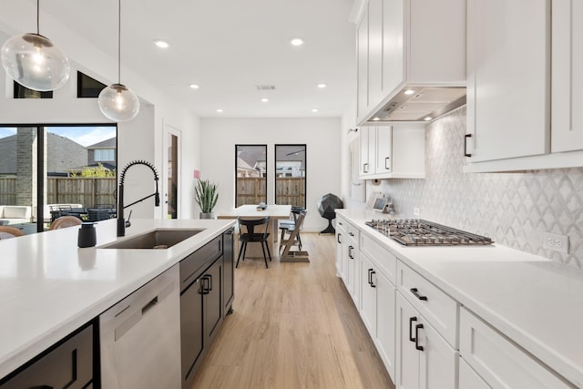 kitchen with stainless steel appliances, white cabinetry, sink, and pendant lighting