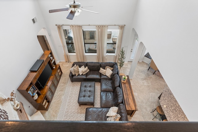 living room featuring ceiling fan and a towering ceiling