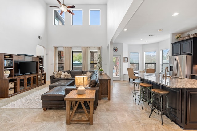 living room featuring ceiling fan, sink, and a towering ceiling