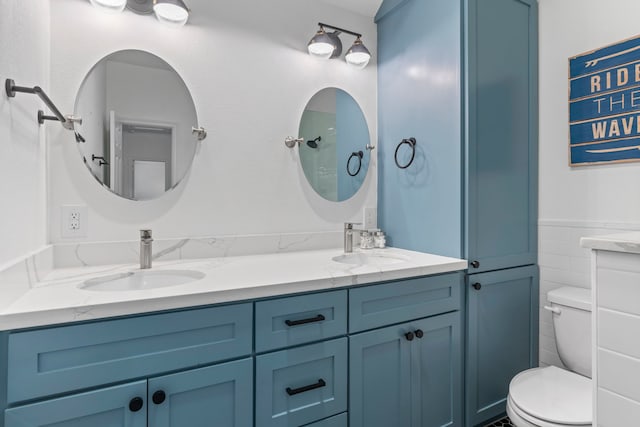 bathroom with vanity, toilet, and tile walls