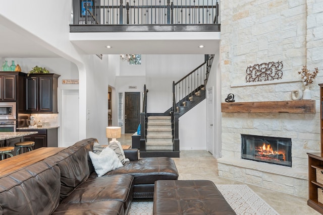 living room with a stone fireplace and a high ceiling