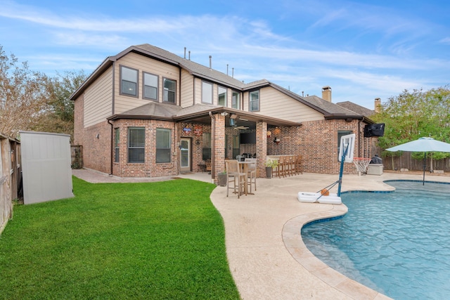 back of property with a fenced in pool, a patio area, a yard, and exterior bar