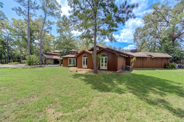 exterior space featuring a front lawn, central air condition unit, and french doors