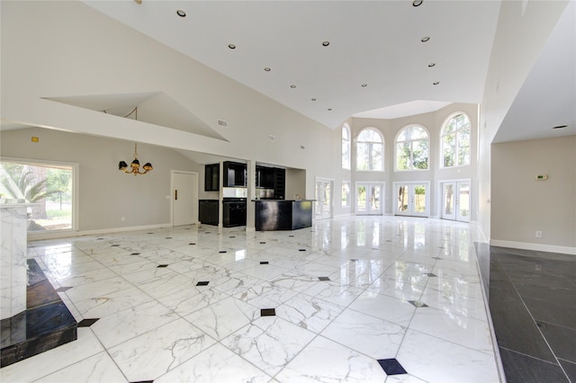 unfurnished living room with a towering ceiling and a chandelier