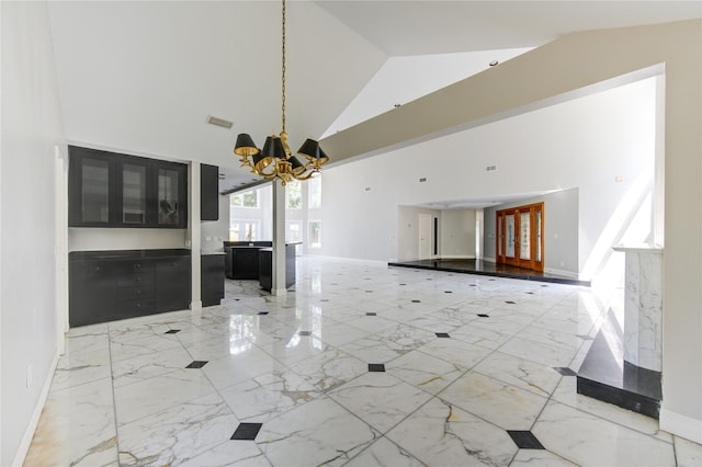 unfurnished living room with high vaulted ceiling and a chandelier