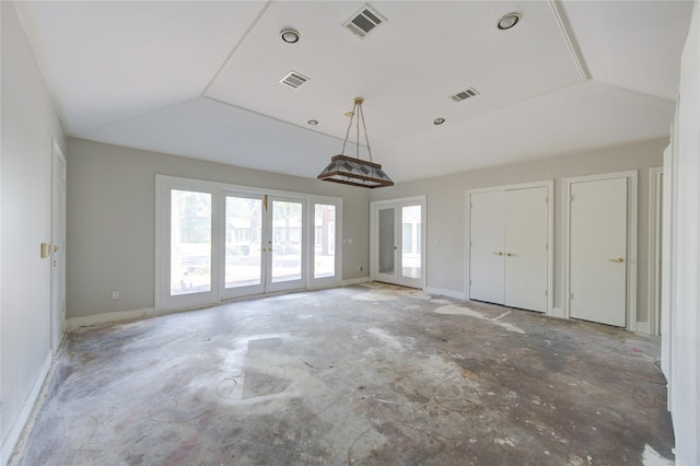 empty room with concrete floors, lofted ceiling, and french doors