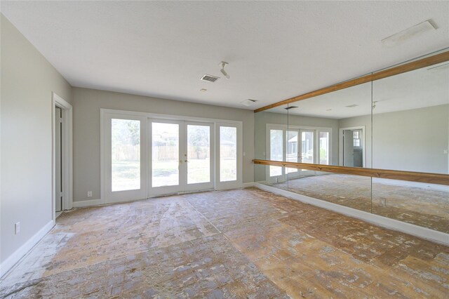 spare room featuring french doors and a healthy amount of sunlight