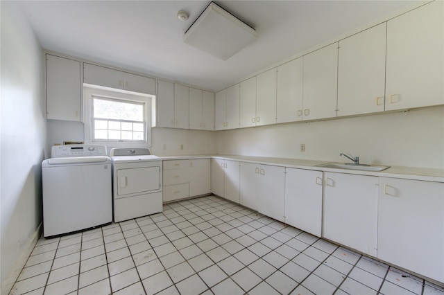 laundry area featuring cabinets, light tile patterned floors, washer and clothes dryer, and sink