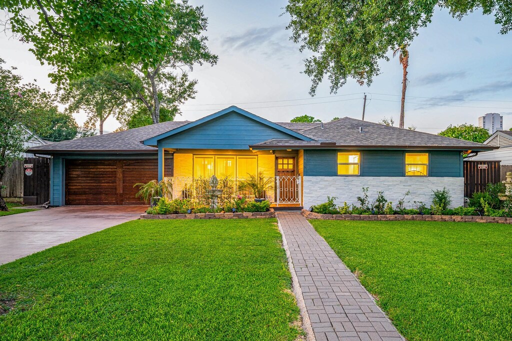 ranch-style home with a garage and a front lawn