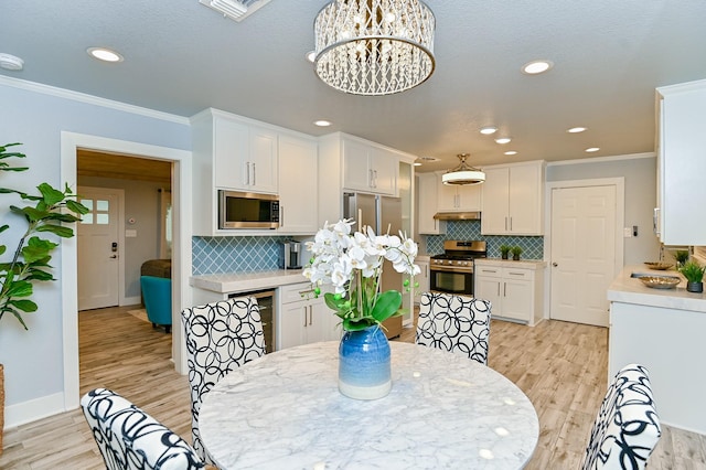 dining area featuring light hardwood / wood-style floors, ornamental molding, and an inviting chandelier