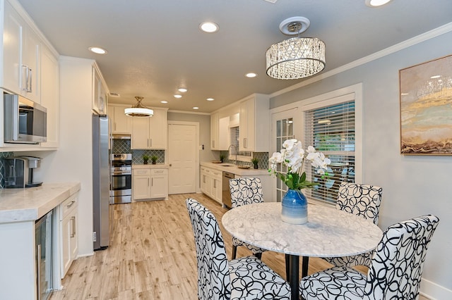 dining space featuring light hardwood / wood-style floors, an inviting chandelier, ornamental molding, and sink