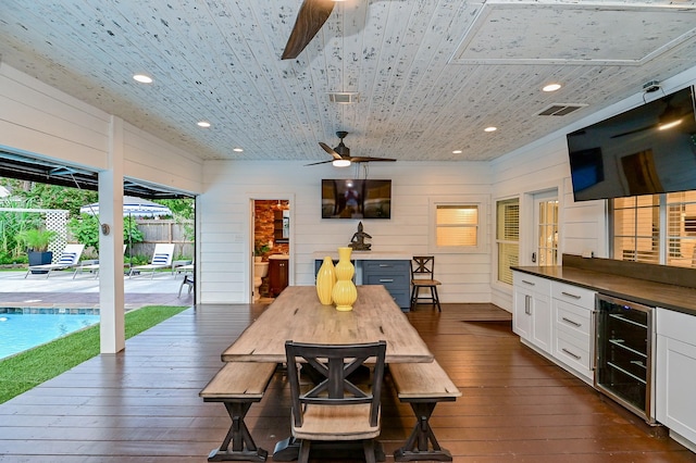 dining room with wine cooler, wooden walls, wooden ceiling, and dark hardwood / wood-style floors