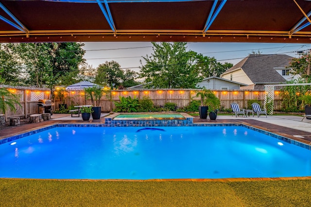 pool at dusk featuring an in ground hot tub and a patio