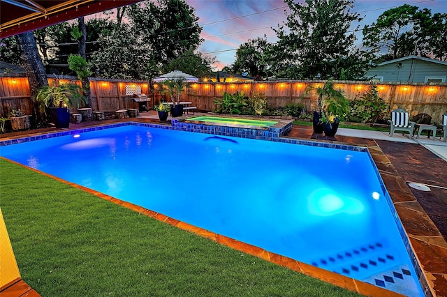 pool at dusk with an in ground hot tub, a yard, and a patio