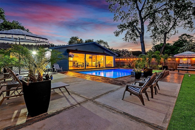 pool at dusk with a patio area