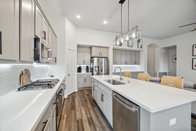 kitchen featuring pendant lighting, sink, an island with sink, appliances with stainless steel finishes, and tasteful backsplash