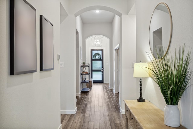 corridor with a notable chandelier and wood-type flooring