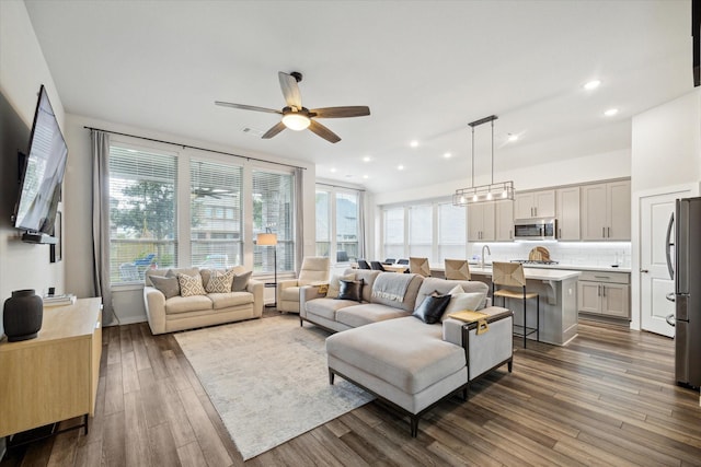 living room featuring ceiling fan, sink, dark wood-type flooring, and a wealth of natural light