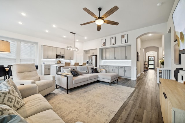 living room featuring ceiling fan and dark wood-type flooring