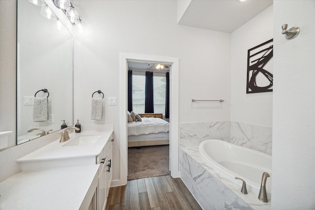 bathroom with vanity, a relaxing tiled tub, and hardwood / wood-style flooring