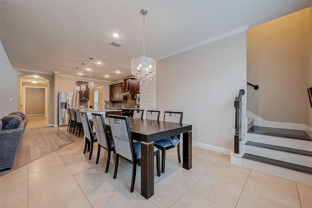 tiled dining space featuring sink, crown molding, and a chandelier