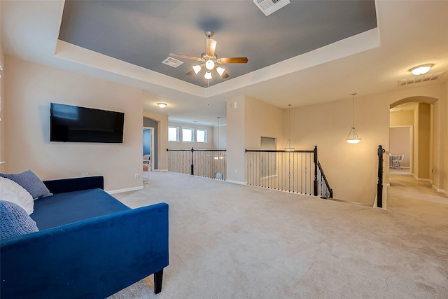 sitting room featuring ceiling fan, a raised ceiling, and light colored carpet