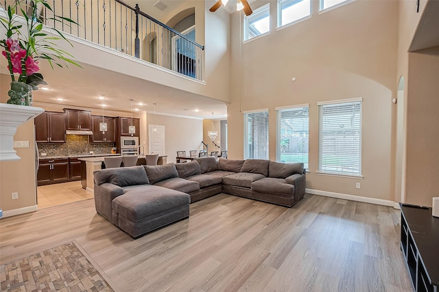 living room with ceiling fan, ornamental molding, and light wood-type flooring