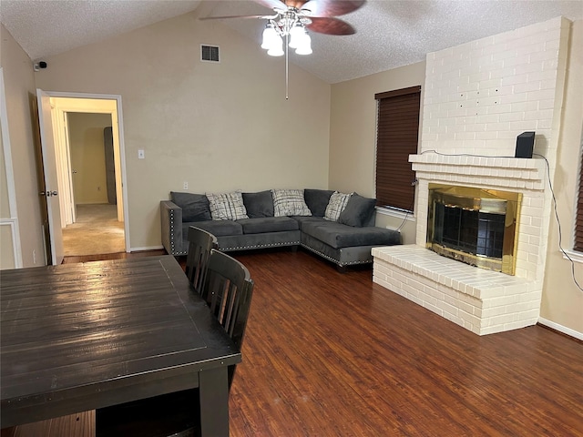 living room featuring a textured ceiling, ceiling fan, dark wood-type flooring, a fireplace, and lofted ceiling