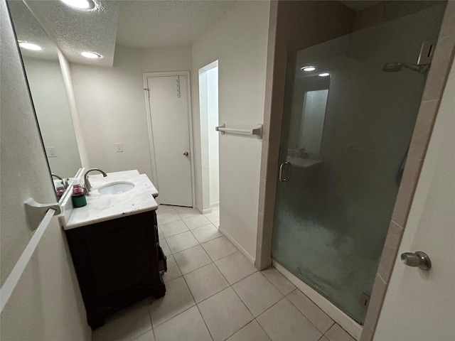 bathroom featuring tile patterned flooring, vanity, a shower with door, and a textured ceiling