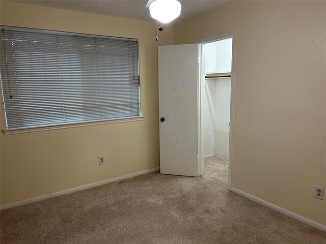 unfurnished bedroom featuring a textured ceiling, light colored carpet, and a closet