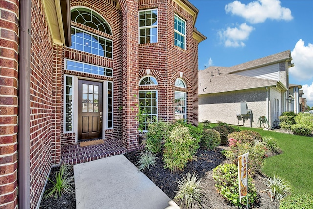 view of exterior entry featuring a lawn