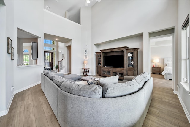 living room with a towering ceiling and light wood-type flooring