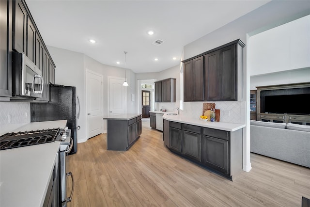 kitchen featuring sink, hanging light fixtures, tasteful backsplash, a kitchen island, and appliances with stainless steel finishes