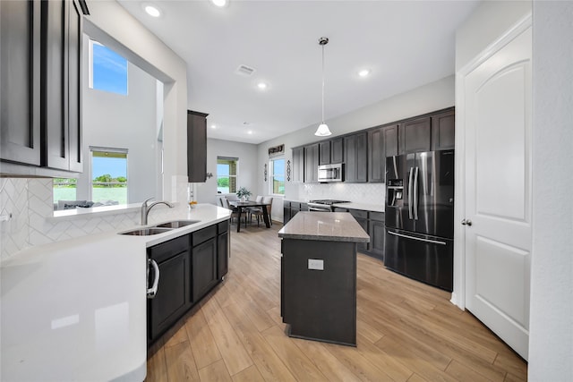 kitchen with backsplash, stainless steel appliances, sink, decorative light fixtures, and a center island