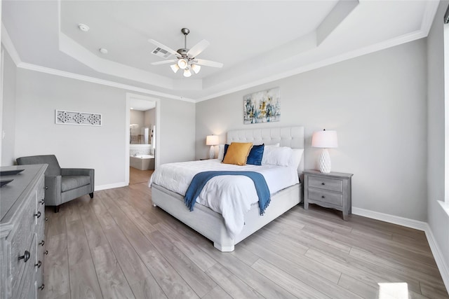 bedroom with ceiling fan, a raised ceiling, light wood-type flooring, and connected bathroom