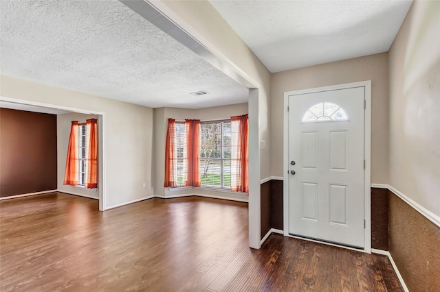 entrance foyer featuring a textured ceiling, plenty of natural light, and dark wood-type flooring