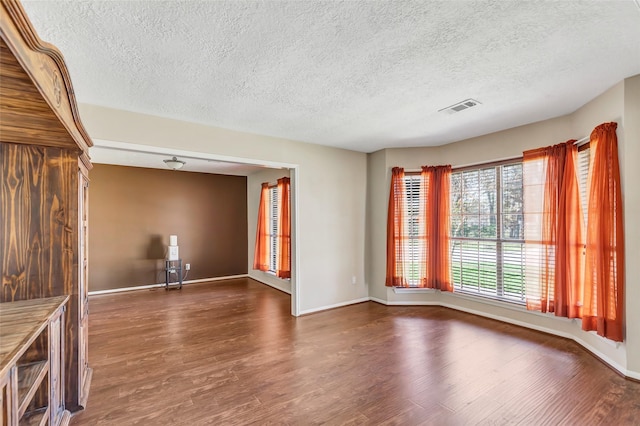 spare room featuring a textured ceiling and dark wood-type flooring