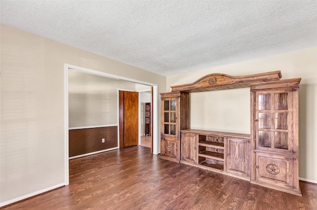 unfurnished living room featuring a textured ceiling and dark wood-type flooring