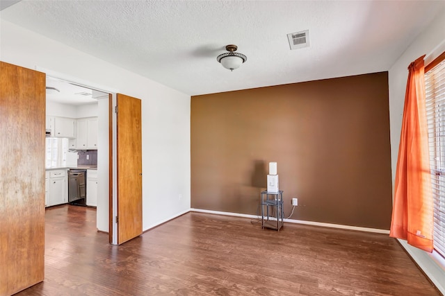 unfurnished room with a textured ceiling and dark wood-type flooring